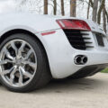 White Audi R8 rear-left view showing large alloy wheel and dual exhausts on the bumper