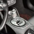 Close-up of a car's center console showing a silver round gear shifter with PRND markings and surrounding control buttons.